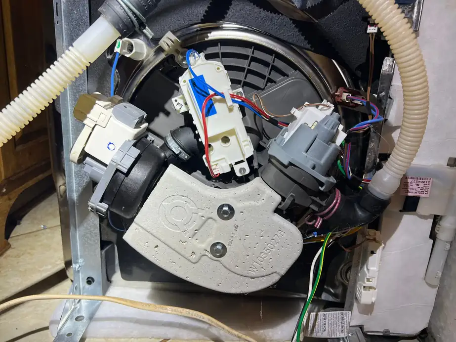Dishwasher drain pump and wiring harness exposed during a repair