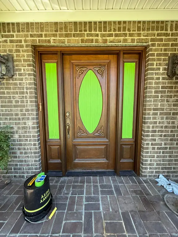 Wood front door with lime-green glass inserts and a cleaning bucket