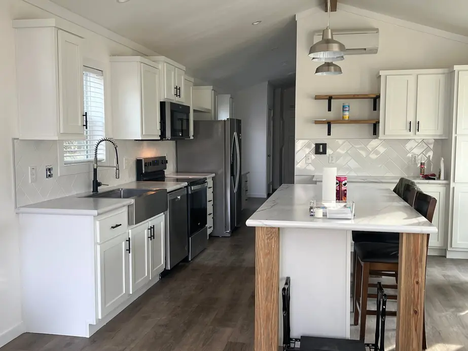 Finished white kitchen with a marble-topped island and open wood shelves