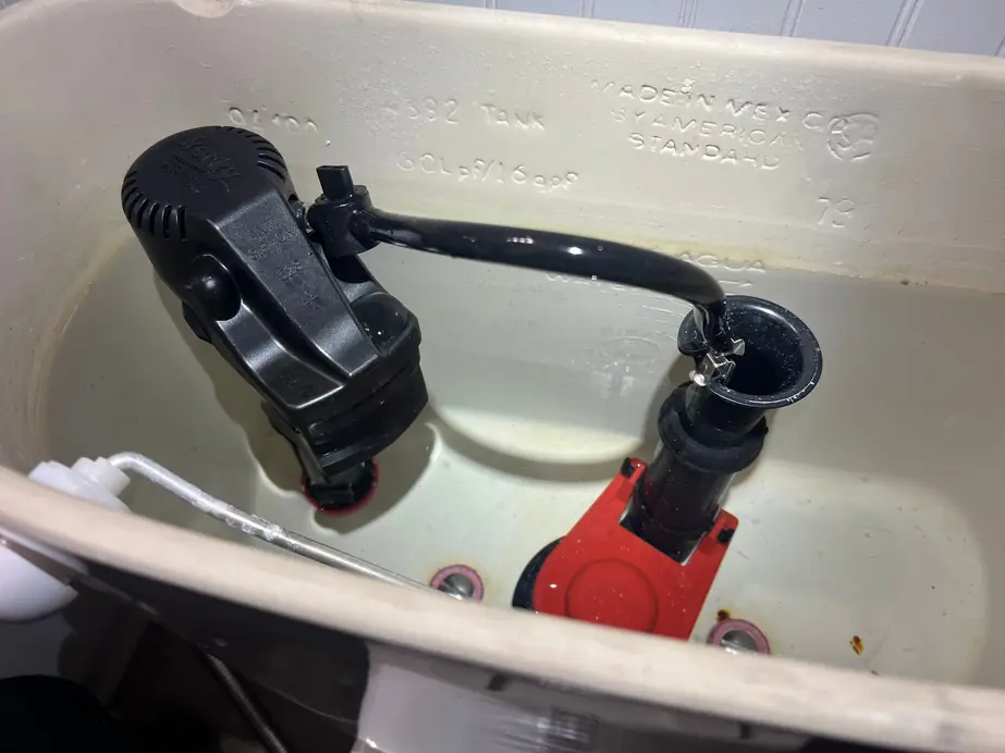 New black and red toilet fill valve installed inside a toilet tank