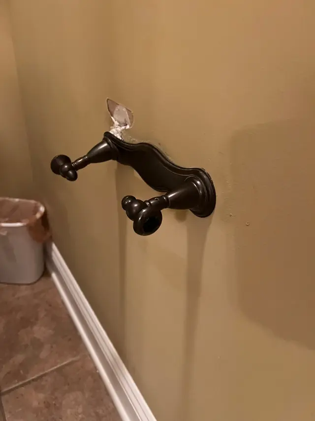 Dark bronze towel bar mounted on a tan bathroom wall
